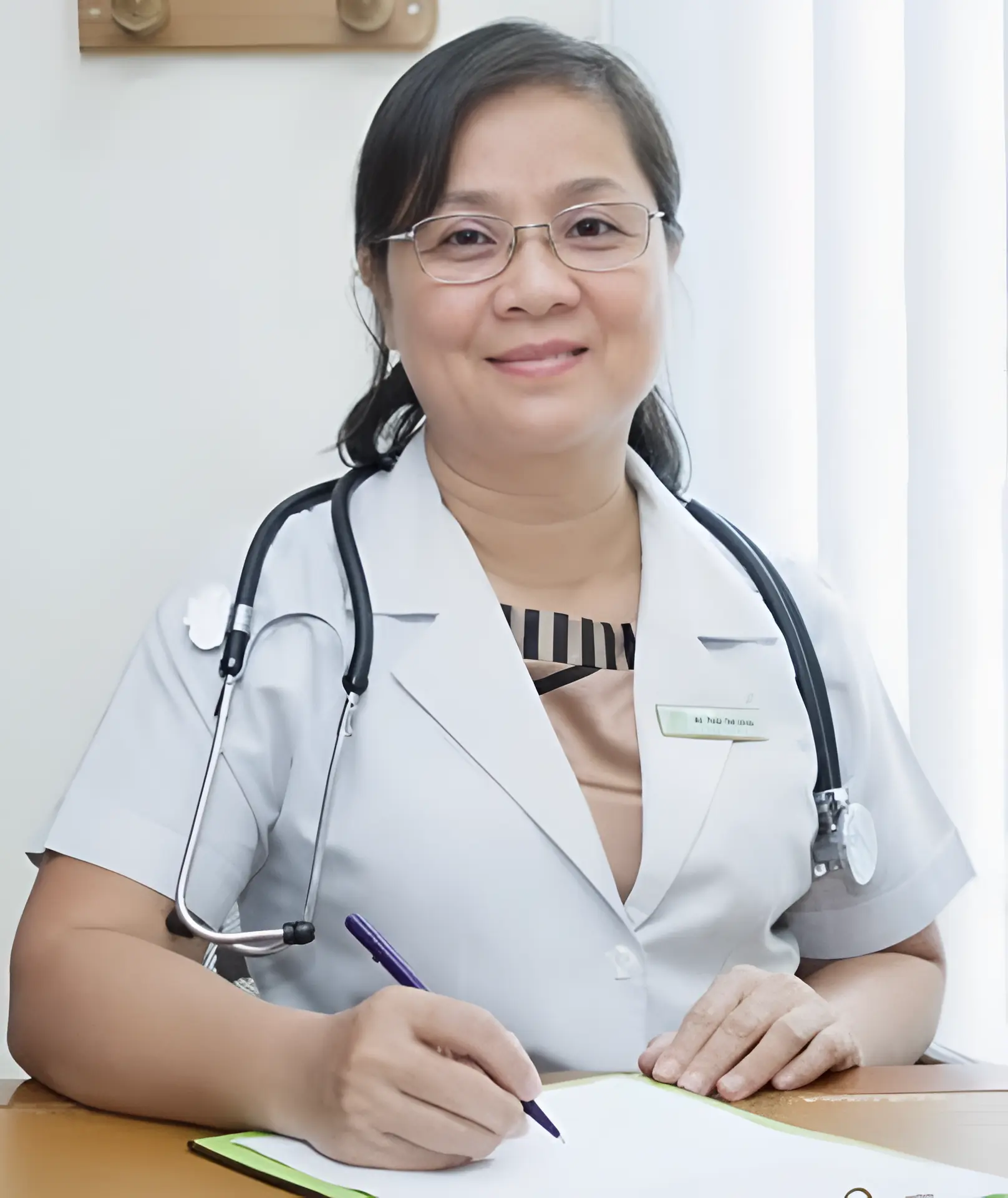 Dr Thai Thi Hoa, seated at her clinic desk with a stethoscope, smiling